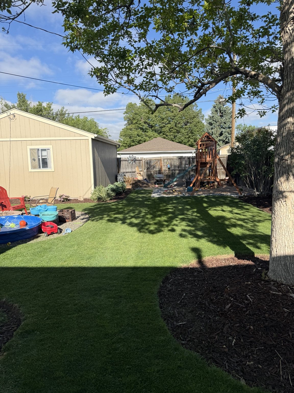 Finished backyard with a play structure at the edge of the lawn